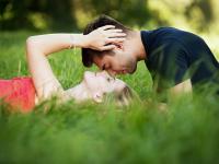 Ein junges Paar liegt zusammen im Gras