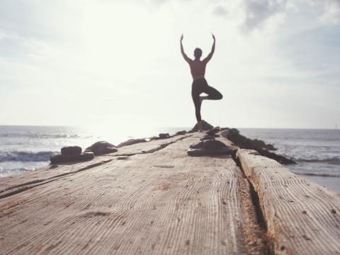 Frau macht Yoga am Meer