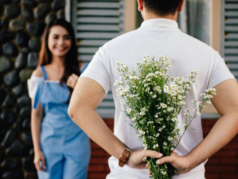 Mann hält Blumenstrauß hinter Rücken